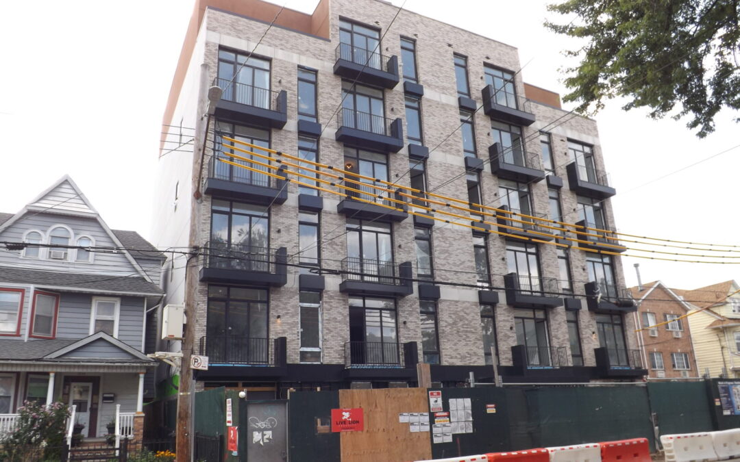 New multifamily apartment building under construction next to older frame houses in East Flatbush, Brooklyn — landlord liability for apartment injuries