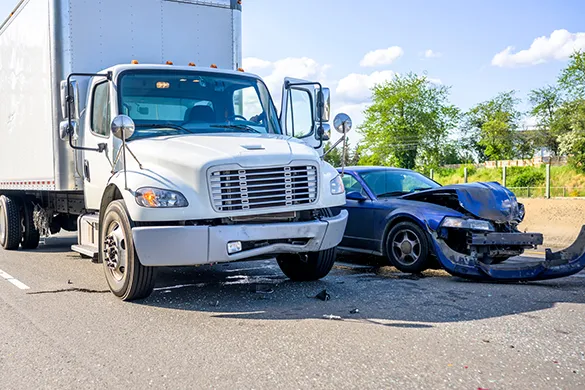 White commercial box truck and a blue sedan with front-end damage after a collision on a New York roadway